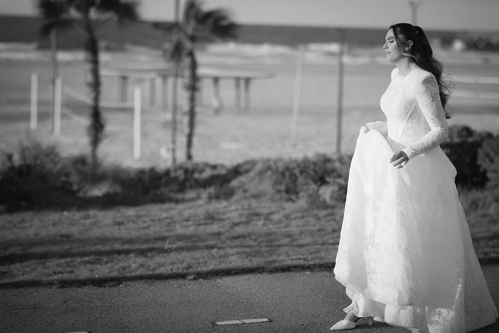 A black-and-white portrait of a bride by the sea.