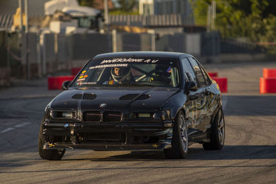 BMW E36 nera con adesivi Inversione A U in derapata tra i cordoli rossi