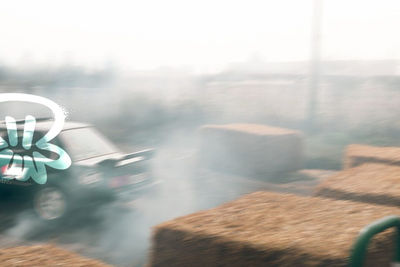 Auto in drift dentro la nuvola di fumo, ripresa dietro le balle di fieno