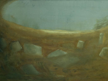 Eine braue Fläche, unterbrochen mit grauen, gräulichen Fragementen; am Horizont eine Öffnung in blau-grau ähnlich wie der Teil einer Linse oder eines Auges; das Bild einer Seele, in dem es nicht viel (mehr) gibt