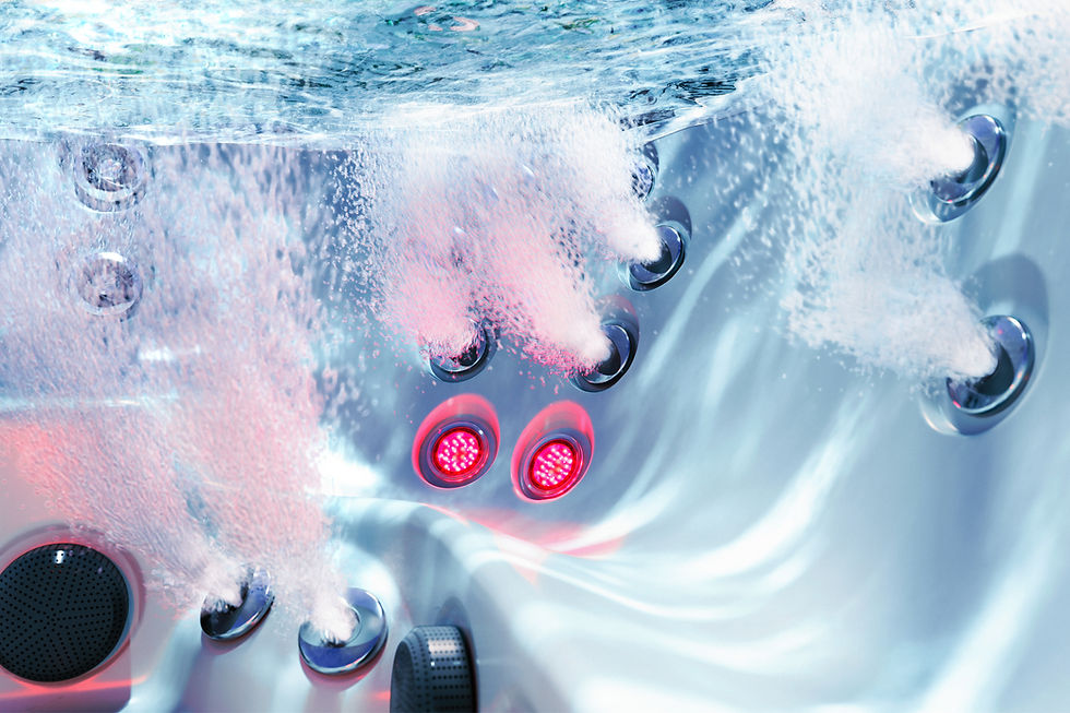 Underwater view of a jacuzzi spa tub with chrome jets blasting bubbles and infrared and red lights in cool blue water.