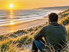 Man kijkt vanuit de duinen uit over zee bij zonsondergang