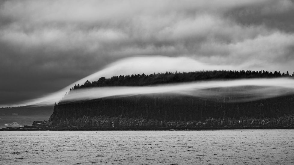 A B&W image showing the View of Bar Harbor from the Water with Low Clouds Drifting Over the Landscape
