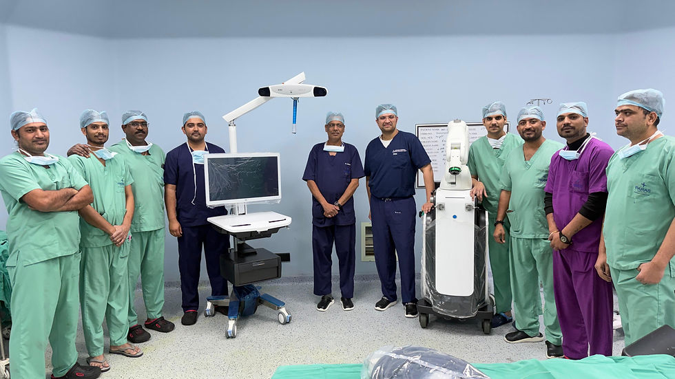 Paras Hospital Udaipur robotic knee replacement Medical team in green, blue, and purple scrubs in an operating room with surgical equipment. They appear calm, posing for a group photo.