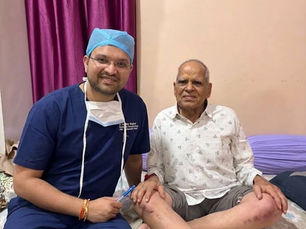 डॉ. आशीष सिंघल के साथ 90 वर्षीय मरीज भुरा लाल तेली, रोबोटिक घुटना प्रत्यारोपण के एक महीने बाद पालथी मारकर बैठे हुए