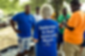 person standing ouside talking to three other people, wearing a blue shirt with white text that says "September is Deaf Awareness Month" with the DeafConnect logo in white underneath the text