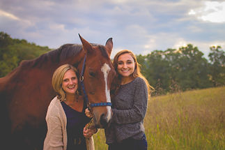 Two smiling women with brown a horse
