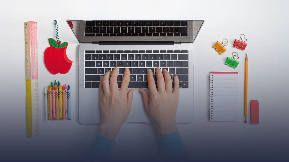 Image of hands typing on a laptop with school supplies on desk