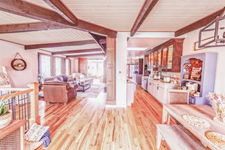 Open concept living area with hardwood floors and exposed ceiling beams in a luxury home.