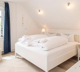 Haus Stranddistel, Wohnung Else weisses Doppelbett in einem hellen, modernen, maritimen Raum