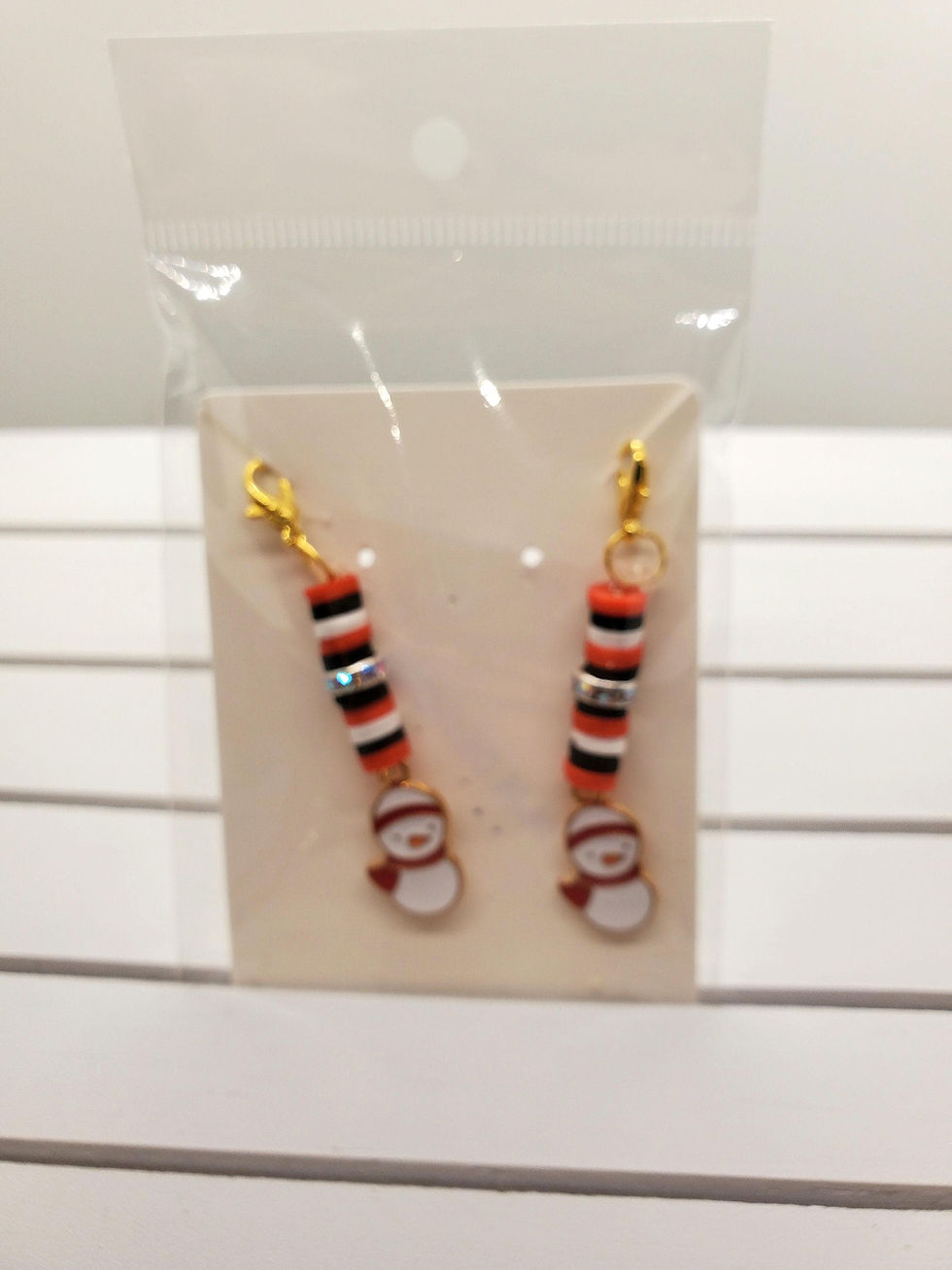 Two beaded snowman zipper pulls on a beige card, with red and black beads.