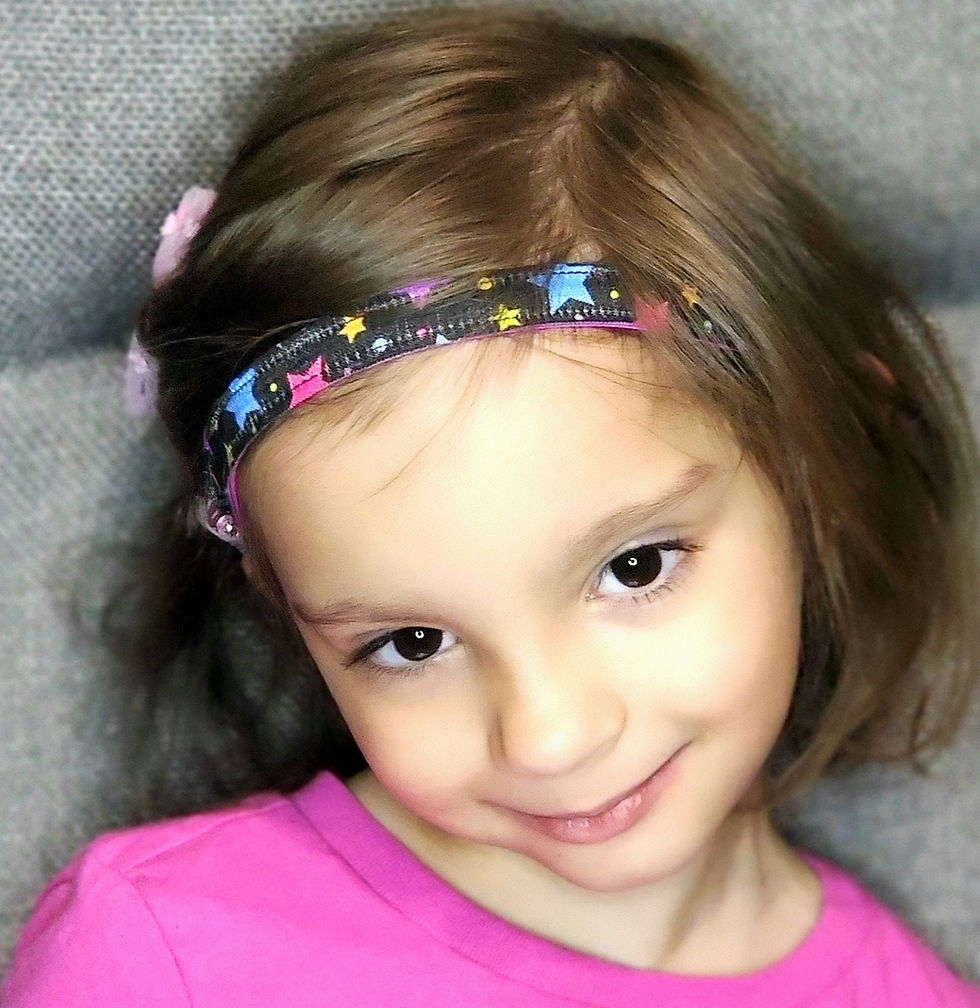 Young girl wearing a headband with stars, smiling, pink shirt, cute photo.