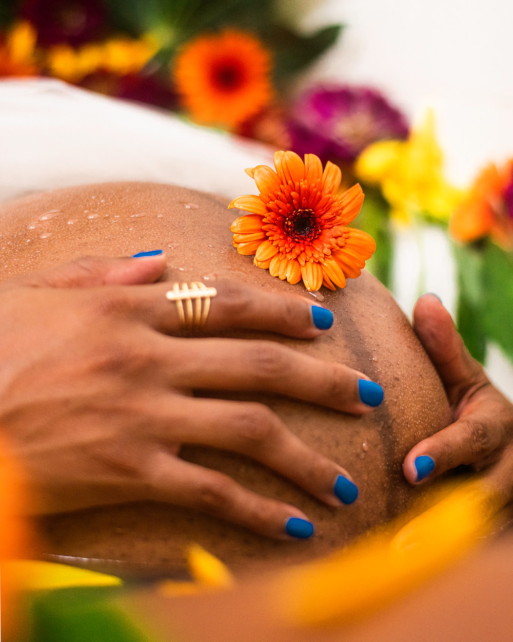 Jennifer's hands on her pregnant stomach with flowers on top and around it