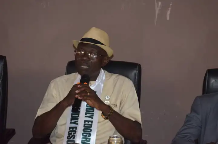 A member in an EGSOSA sash addressing a gathering at a microphone