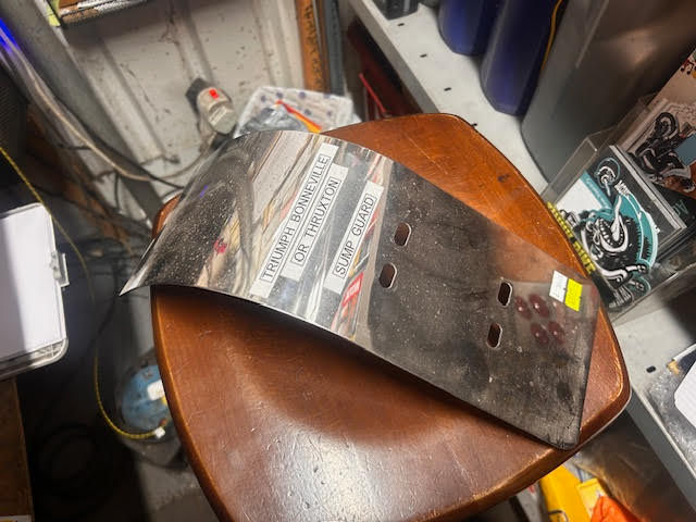 Shiny metal motorcycle part on brown table with newspaper background Malcsmotorbikespares