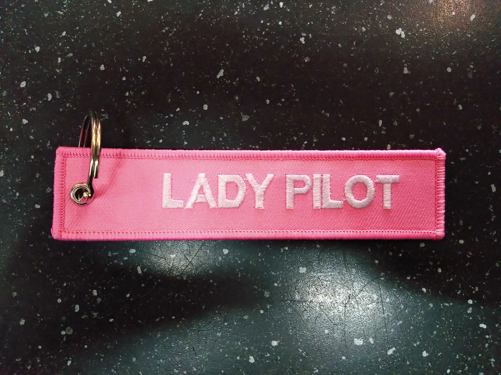 Pink Lady Pilot keychain with white letters, promoting female pilots