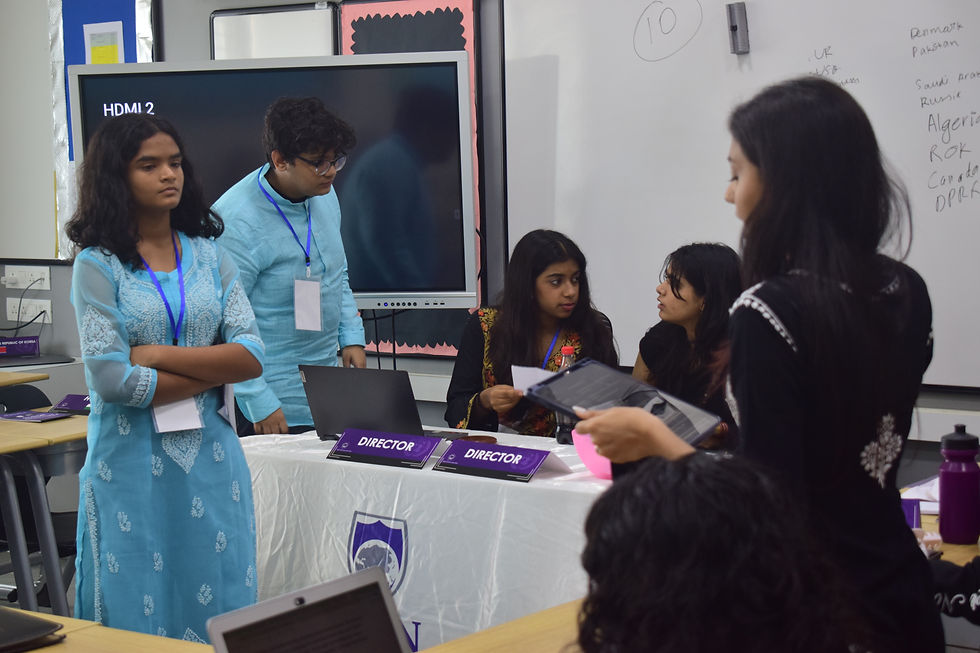 Picture of 2 delegates debating while others enthusiastically discuss, from JBCN Osh MUN