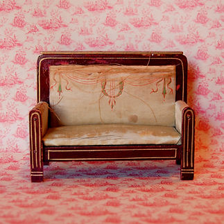 An old German miniature silk sofa from the late 1800s appears frayed.