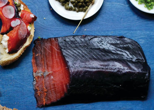 Blueberry salmon gravlax on a blue countertop.