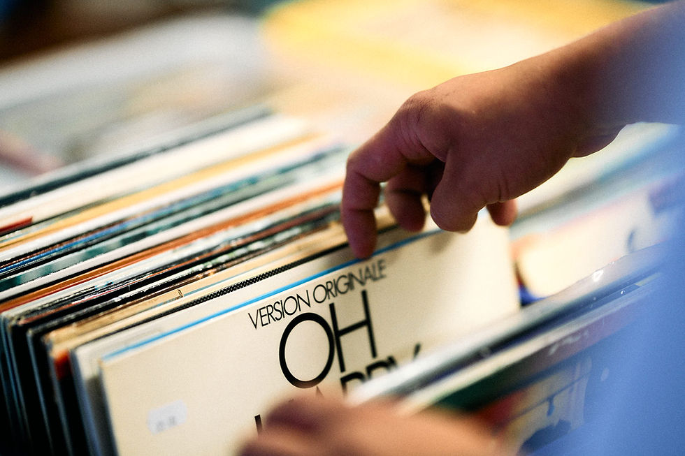 Hand väljer en vinylskiva med texten VISION ORIGINALS OH HAPPY HEM.