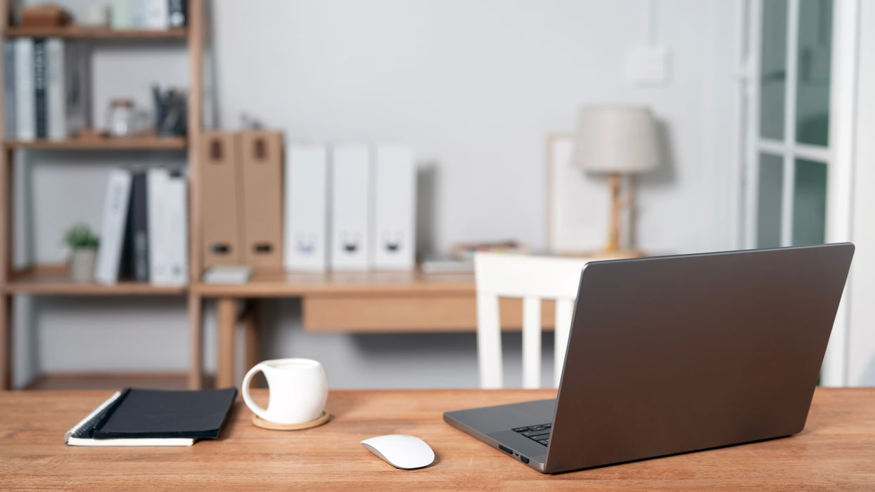 Laptop, anteckningsbok och mugg på ett skrivbord