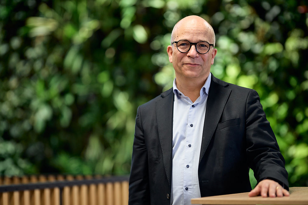 Man in glasses, blazer and shirt, smiling, looking at camera. CoForma Bostad
