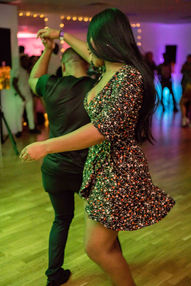A couple dancing Kizomba, with the leader skillfully executing a turn and lifting their hand over his head