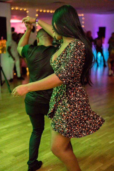 A couple dancing Kizomba, with the leader skillfully executing a turn and lifting their hand over his head