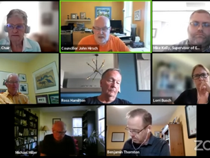 A virtual meeting with eight people in individual boxes. Backgrounds show varied home offices. The mood is focused. Some boxes have text labels.