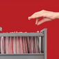 Hand hovering over an open file drawer filled with folders against a solid red background.