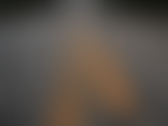 Cracked rural road with faded yellow lines leads into misty distance, flanked by trees. Moody and desolate atmosphere.