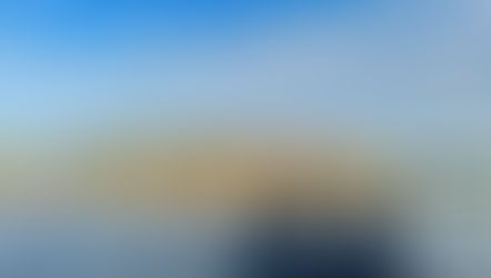 Two black Adirondack chairs on a dock by a calm lake, facing autumn trees under a blue cloudy sky; SnapEdit watermark.