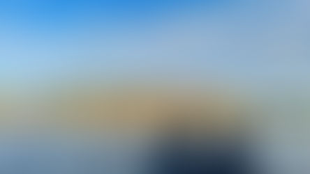Two black Adirondack chairs on a dock by a calm lake, facing autumn trees under a blue cloudy sky; SnapEdit watermark.