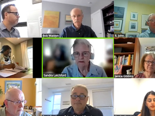 A virtual meeting with nine participants in separate boxes. One person is speaking while others listen. Various home office backgrounds.