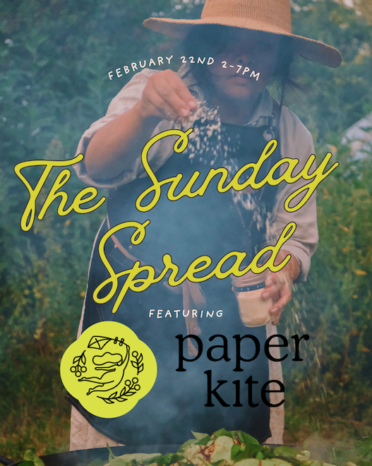 A person in a hat sprinkles seasoning over food outdoors. Text reads "The Sunday Spread, February 22nd 2-7PM" featuring "paper kite."