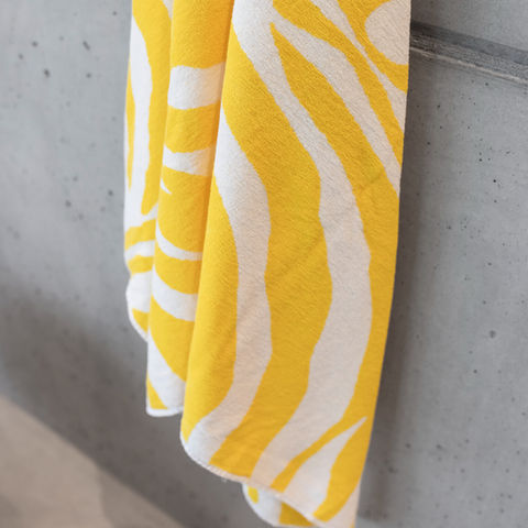 Yellow and white zebra towel hanging on a cement wall