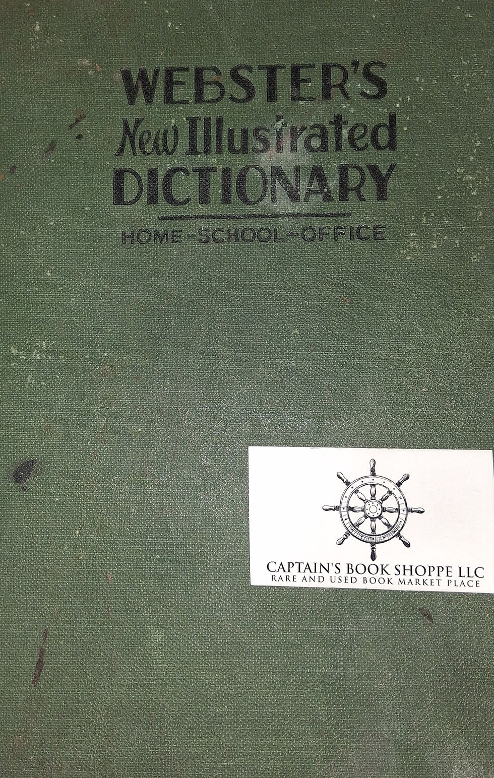 Green cover of Webster's New Illustrated Dictionary with vintage texture. A business card of Captain's Book Shoppe LLC is attached.