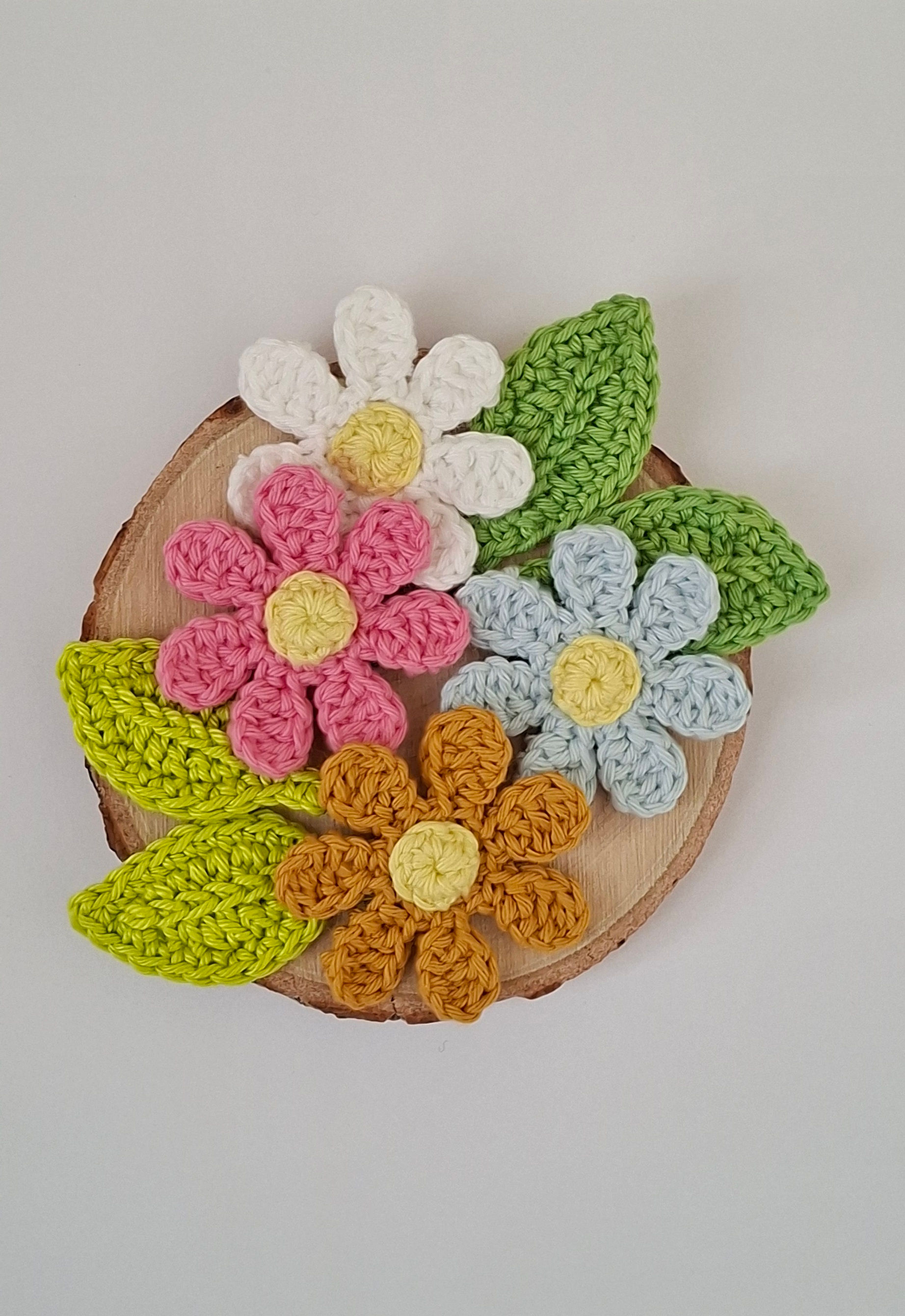 Handmade white crochet daisy with a yellow center green leaves, crafted from soft cotton wool yarn