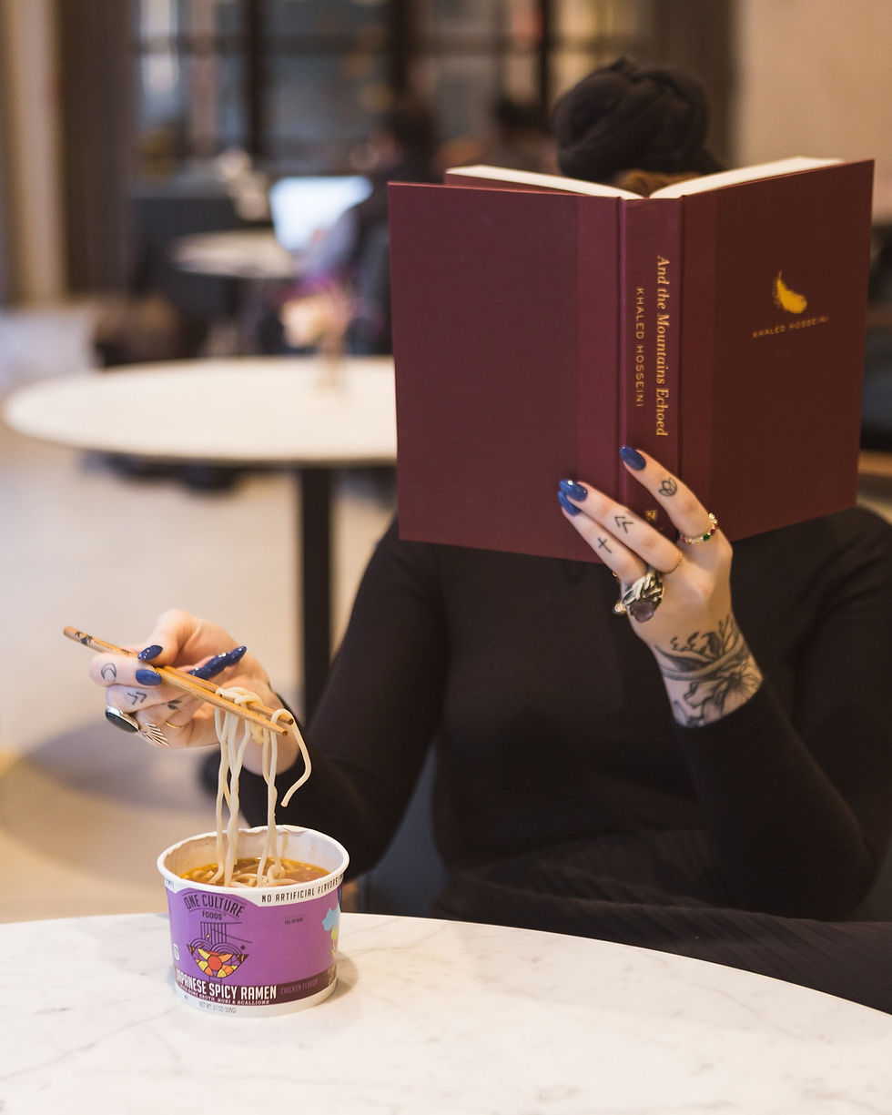 Woman with hand tattoos at table reading while eating sushi (credit: Creative Commons)