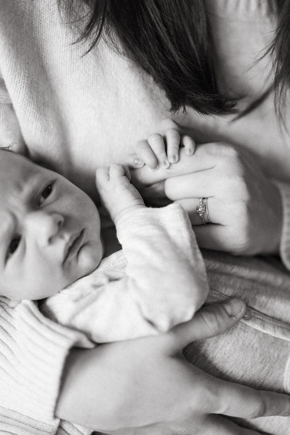 mother snuggling newborn baby on bed during lifestyle newborn session in DC