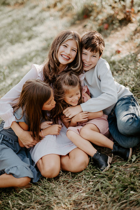 Children laughing during golden fall leaves during an outdoor photography session in the DMV