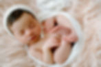 Baby girl curled up on neutral blanket during posed newborn session in Charlottesville