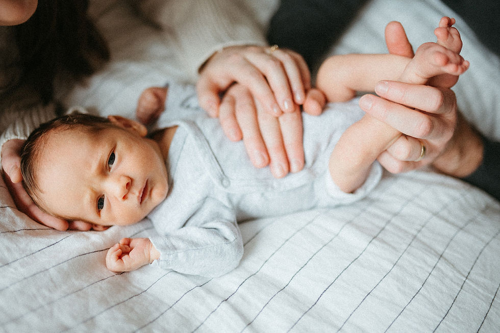 amily of three holding newborn baby on bed during Washington DC lifestyle newborn session