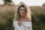 Portret van een vrouw in zachte avondzon terwijl ze zelfverzekerd in de camera kijkt.