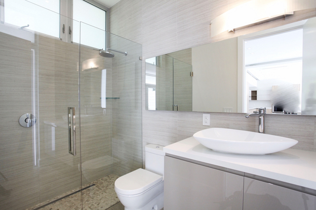 Frameless glass shower enclosure with modern vanity mirror in a contemporary bathroom
