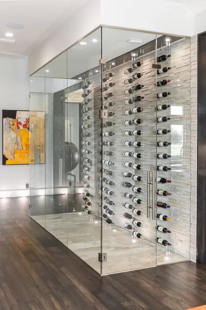 Custom glass wine cellar enclosure with floor-to-ceiling bottle display in a luxury home