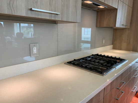 Back painted glass backsplash installed behind a kitchen cooktop in a modern residential kitchen