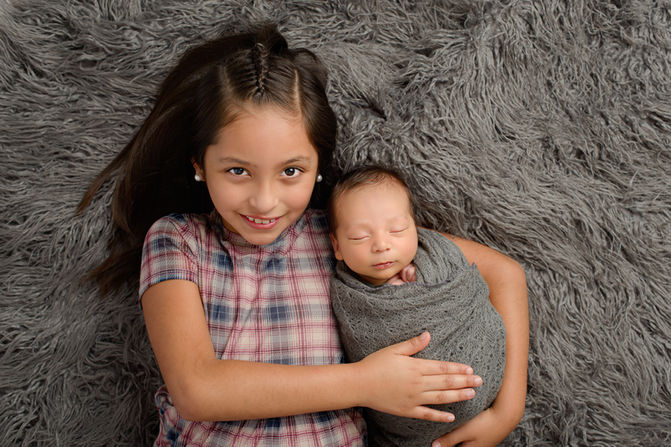 Newborn baby boy posing with sister