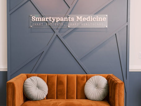 Smartypants Medicine luxury office with logo on navy blue geometric wall and burnt orange couch