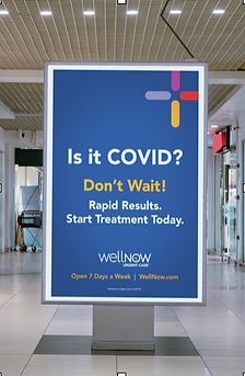 Photo of WellNow vertical billboard in mall promoting COVID testing and treatment